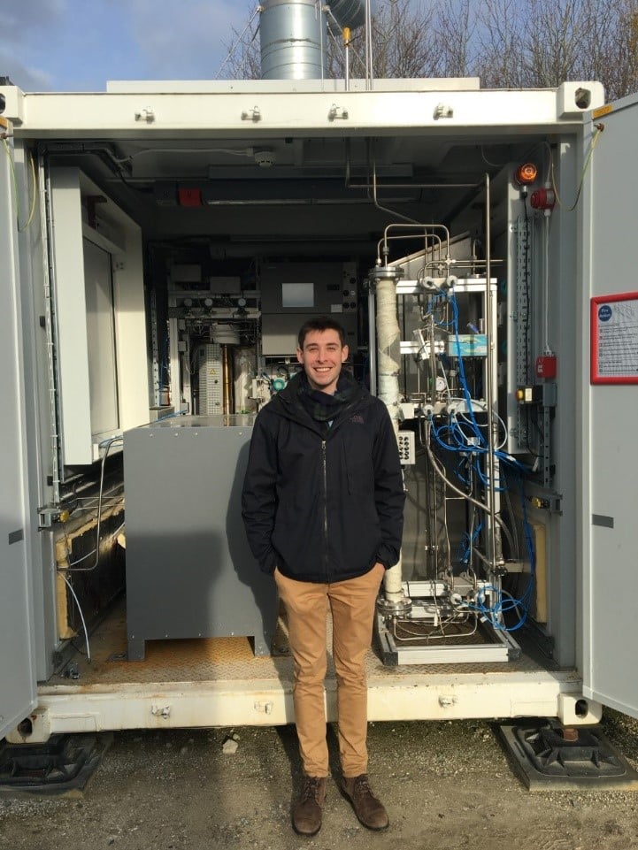 Zac Cesaro outside electrolyser Zac Cesaro (2nd year DPhil in Engineering Science) working at UK Demonstrator, in front of electrolyser and Haber-Bosch synthesis loop.