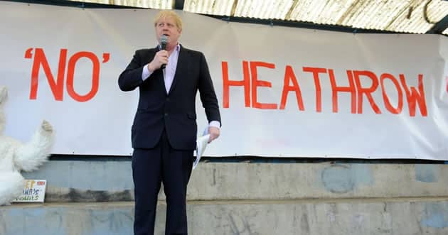Boris Johnson Heathrow Boris Johnson with a microphone in hand stands on a stage in front of a sign saying No Heathrow